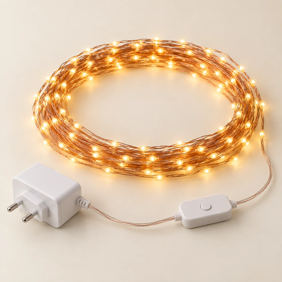 Warm-white copper-wire string lights coiled beside a plug adapter and inline controller