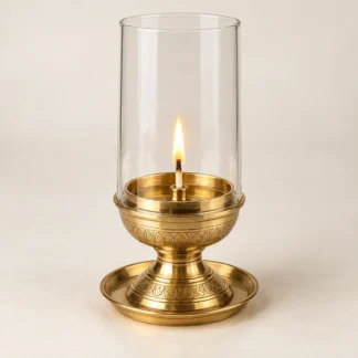 Brass Akhand diya with a clear glass chimney and a lit cotton wick